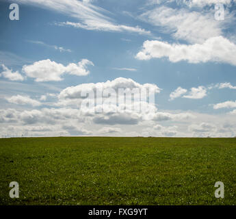 Beautiful day fluffy clouds in blue sky above grassy hill Stock Photo