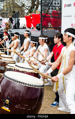 Taiko Drummers, kumi-daiko concert. Side view of row of children and teenagers in traditional drumming costume, beating line of nagado-daiko drums. Stock Photo