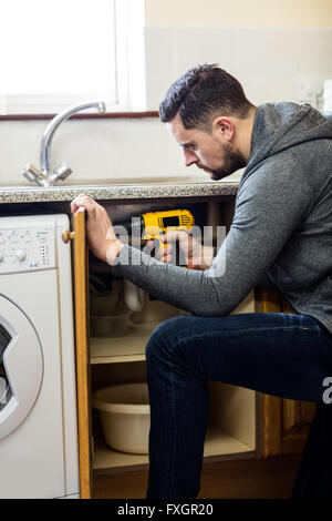 Manual worker drilling a hole in kitchen Stock Photo