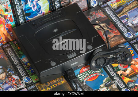 A PAL Sega Saturn console with a standard controller on a bed of its best games. Stock Photo