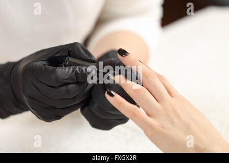 Manicurist paints customer nails in black Stock Photo