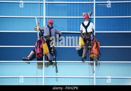 Two construction workers working at height on modern commercial skyscraper. Stock Photo