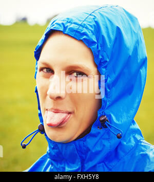 Young woman sticking tongue out on a rainy day Stock Photo