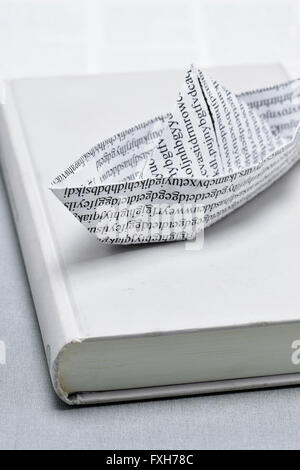 closeup of a paper boat, made with a printed paper with non-sense words, on a book Stock Photo