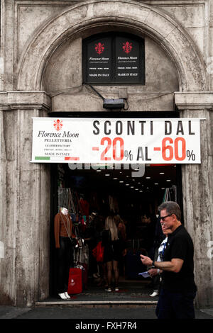 Pedestrians walk past a store advertising 20% 60% price discounts in Rome, Italy Stock Photo