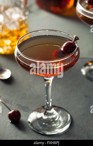 Glass of iced Manhattan cocktail with cherry on light background ...