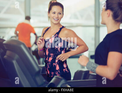 Smiling women talking on treadmills at gym Stock Photo