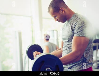 Focused man doing barbell biceps curls at gym Stock Photo