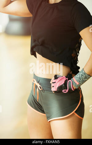 Midsection fit woman wearing short running shorts at gym Stock Photo