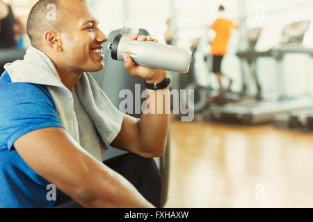 Taking a break and drinking water. Young sportive strong man in black wear  have workout day in gym Stock Photo - Alamy