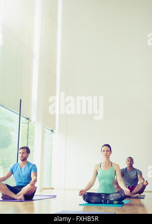 Yoga class sitting in lotus position Stock Photo