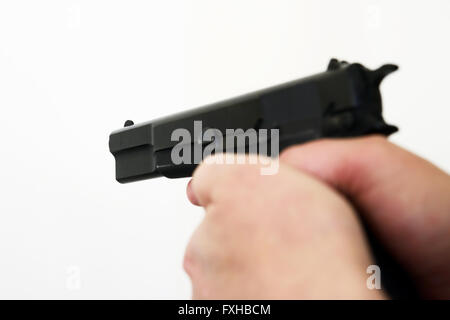 Hands of a man pointing a pistol on light background Stock Photo