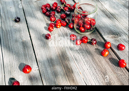Large and delicious cherries are chaotically arranged on a wooden board Stock Photo