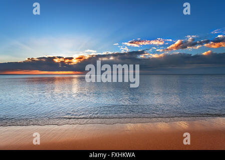 Beautiful sunset over sea with reflection in water, majestic clouds in the sky. Stock Photo