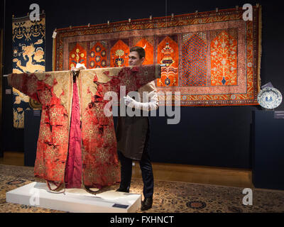 London, UK. 15 April 2016. A Christie's employee tends to a metal-thread embroidered velvet coat (Chapan), from Bukhara, 19th century, est. GBP 5000-8000. Christie's presents highlights from the upcoming sales of Oriental Rugs and Carpets (19 April) as well as Art of the Islamic and Indian Worlds (21 April). Stock Photo