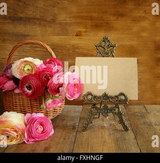 pink flowers in the basket next to empty card. mother's day concept. copy space.