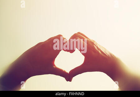 image of hands in the form of heart against the sunset sky. vintage filtered Stock Photo