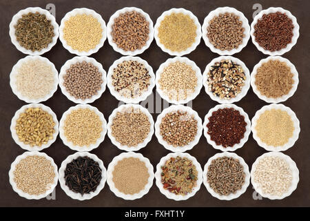 Large cereal and grain food selection in porcelain bowls over lokta paper background. Stock Photo