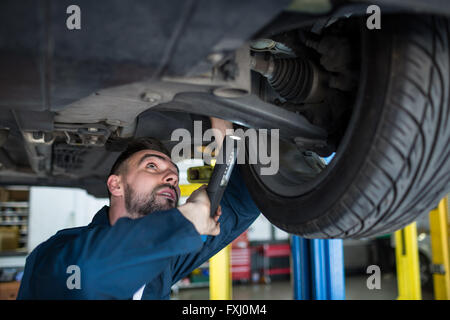 Mechanic examining car tyre using flashlight Stock Photo