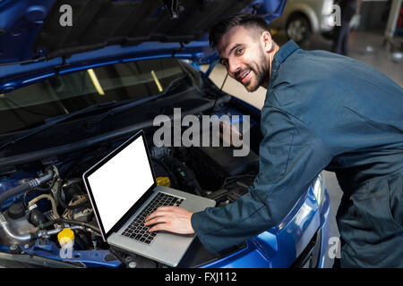 Mechanic examining car engine with help of laptop Stock Photo