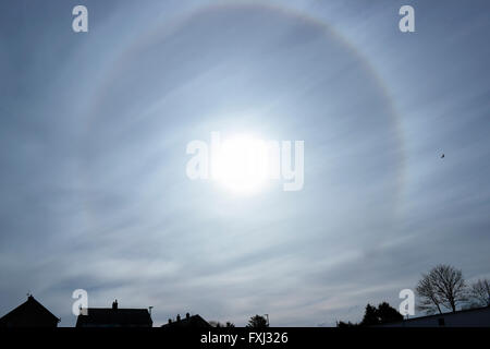 An unusual 22° halo circular rainbow around the sun caused by diffraction of light through ice crystals in the atmosphere. Sun Dog. Stock Photo