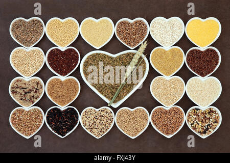 Grain and cereal food selection in heart shaped porcelain bowls over lokta paper background. Stock Photo