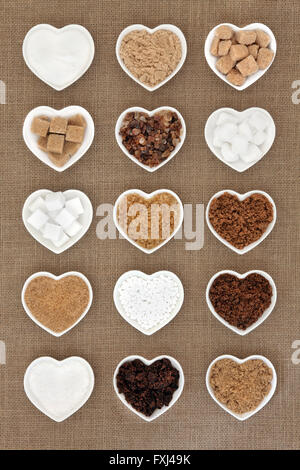 Brown and white sugar selection in heart shaped bowls over hessian background. Stock Photo