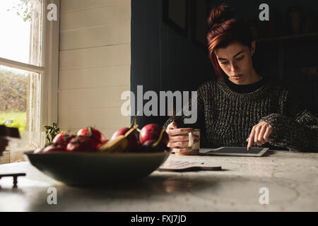 Young woman holding coffee mug and using digital tablet Stock Photo