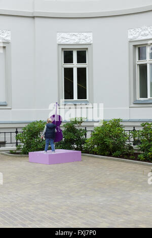 the little boy has a good time with a monument in the form of a violin Stock Photo