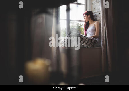 Young woman sitting on the window sill Stock Photo