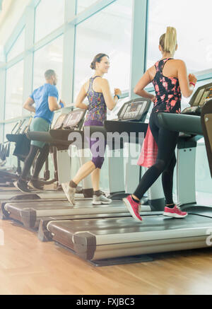 Man and women jogging on treadmills at gym Stock Photo