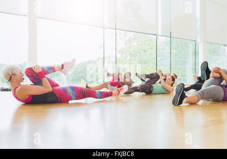 Fitness instructor guiding exercise class stretching legs Stock Photo