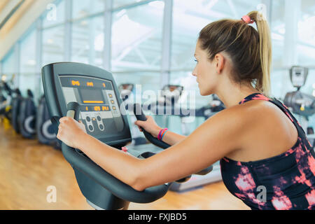 Woman riding exercise bike at gym Stock Photo