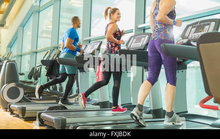 Man and women running on treadmills at gym Stock Photo