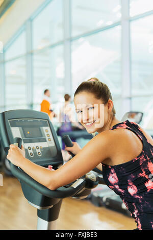 Portrait smiling woman on exercise bike at gym Stock Photo