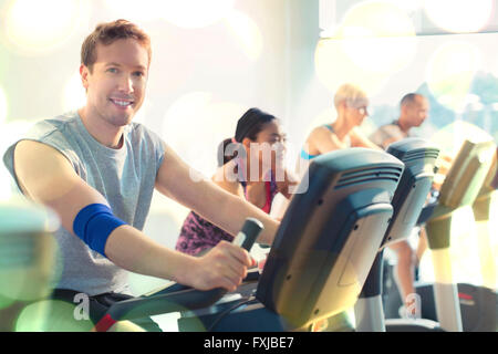 Portrait smiling man riding exercise bike at gym Stock Photo