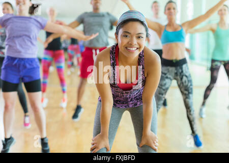 Portrait smiling woman resting with hands on knees in exercise class Stock Photo