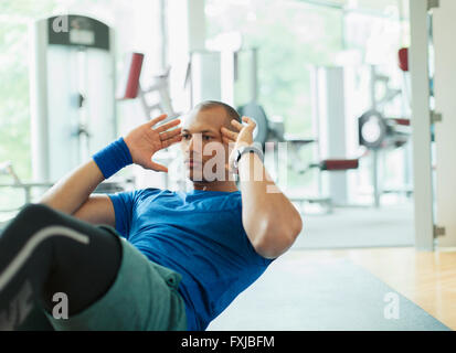 Focused man doing sit-ups at gym Stock Photo