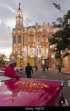 Vertical view of classic American cars parked outside the Grand Theatre at sunset in Havana, Cuba. Stock Photo