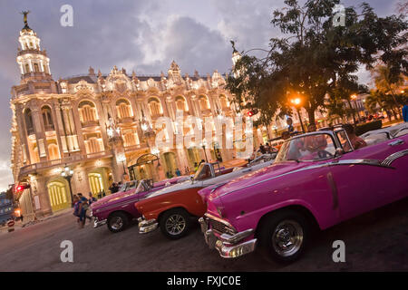 Horizontal close up of vintage American cars infront of the Grand Theatre at sunset in Havana, Cuba. Stock Photo