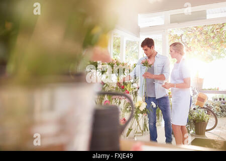 Florist helping man choosing flowers in flower shop Stock Photo