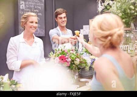 Florist giving woman rose in flower shop Stock Photo