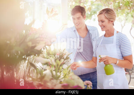 Florist spraying flowers with water bottle in flower shop Stock Photo