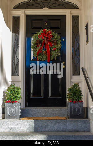 A Christmas wreath or garland  hanging on a front entrance door on a house in the Beacon Hill district of Boston, Boston,  Massachusetts, USA Stock Photo