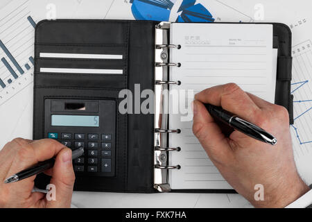 Businessman thinks on the calculator and  writes, as background Stock Photo