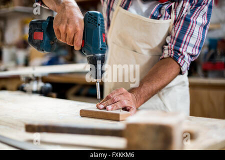 Carpenter drilling a hole in a wooden plank Stock Photo