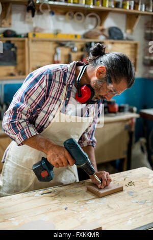 Carpenter drilling a hole in a wooden plank Stock Photo