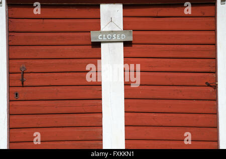 Written closed sign hanging on two red old wooden doors Stock Photo