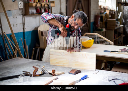 Carpenter drilling a hole in a wooden plank Stock Photo