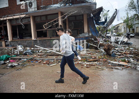 Dolores, Uruguay. 16th Apr, 2016. A woman walks with her child in front of damaged buildings after a tornado in Dolores, Uruguay, on April 16, 2016. A tornado thrashed the city of Dolores, western Uruguay, on Friday, leaving four people dead and others seriously injured, the country's emergency services said. Credit:  Nicolas Celaya/Xinhua/Alamy Live News Stock Photo